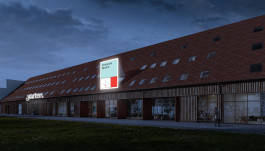 Mock-up eines Gebäudes mit rotem Ziegeldach und moderner Holzfassade bei Abenddämmerung. Ein beleuchtetes Schild mit der Aufschrift „Creative Space“ und einer grafischen Farbaufteilung in Blau, Weiß und Rot weist den Weg. Der Schriftzug „yarten“ ist ebenfalls an der Fassade beleuchtet.